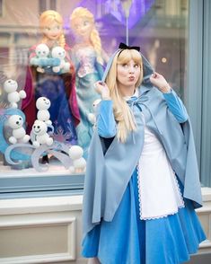 a woman dressed up in a blue and white outfit standing next to a store window