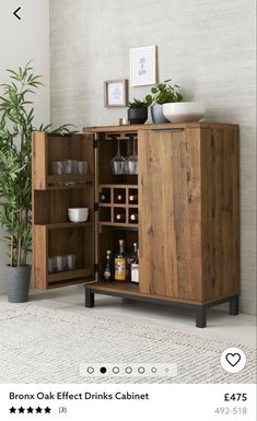 a wooden cabinet filled with lots of bottles and glasses next to a potted plant