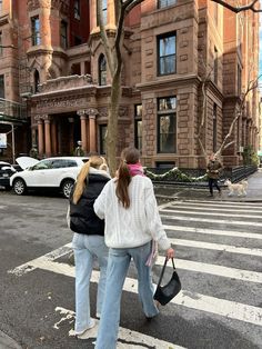 two women crossing the street in front of an old building