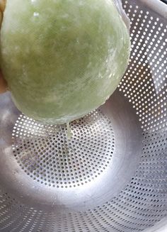 a green apple is sitting in a strainer