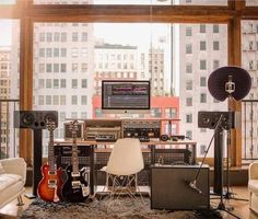 a living room filled with lots of furniture and musical equipment in front of a large window