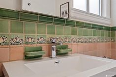 a white sink sitting under a bathroom mirror next to a green tiled wall and window