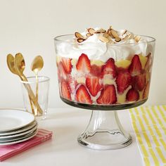 a trifle with strawberries and whipped cream in a glass dish on a table