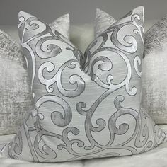 two silver pillows sitting on top of a bed