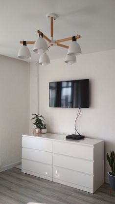 a flat screen tv mounted to the side of a white cabinet in a living room