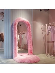 a pink mirror sitting on top of a wooden floor next to a shelf filled with clothes