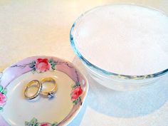 two wedding rings sitting on top of a plate next to a glass container with another ring in it