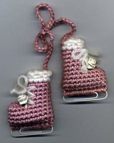 two pink and white purses are hanging from hooks on a gray surface, one is made out of yarn