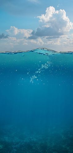 an underwater view of the ocean with clouds in the sky