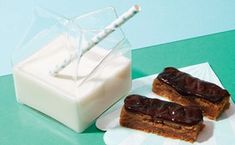 two pieces of cake sitting on top of a plate next to a container of milk