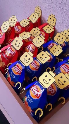 a box filled with lots of different types of candy bar wrapped in paper and cut out to look like faces