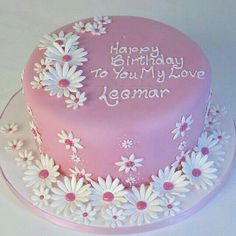 a pink birthday cake with white daisies on it