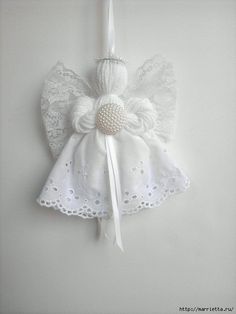 a white angel ornament hanging on a wall with a ribbon around it's neck