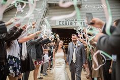 a bride and groom walk through confetti streamers as they exit the barn