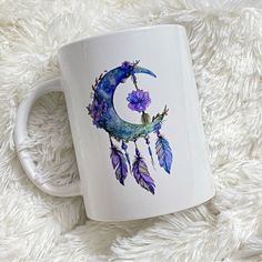 a white coffee mug with purple flowers and a crescent moon painted on the inside of it