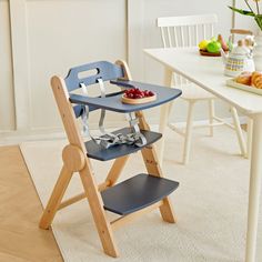 a small child's high chair sitting in front of a table with food on it