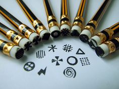 a group of gold and black pens sitting on top of a white table next to each other