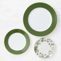 three green and white plates sitting next to each other on a marble counter top,