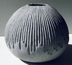 a black vase sitting on top of a white table next to a wall and floor