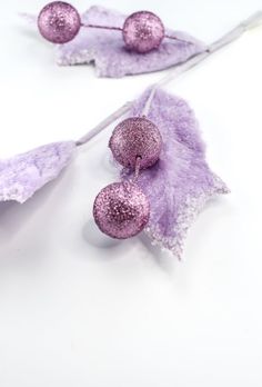 two pieces of purple glitter sitting on top of a leaf