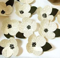 paper flowers made out of old book pages on a white tablecloth with black trim