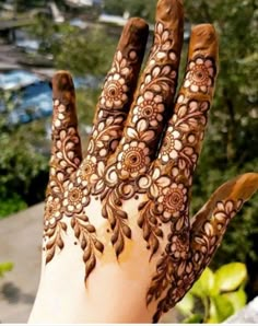 a hand with henna on it and trees in the background