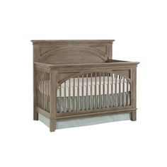 a wooden crib with white sheets on it