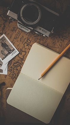 a notepad with writing on it next to an old camera and some photos are lying on the table