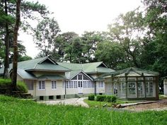 a house in the middle of some trees and grass with lots of windows on it