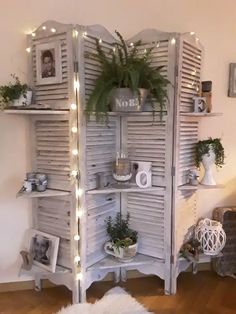 a white shelf with plants and pictures on it