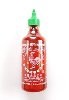 a bottle of hot chili sauce on a white background with chinese writing in the bottom corner