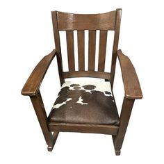 a wooden chair with a cow print seat pad on it's back and arms