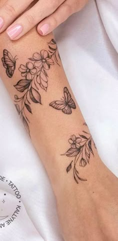 a woman's arm with flowers and butterflies on it