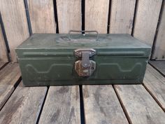 an old green metal box sitting on top of a wooden floor