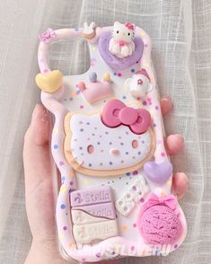 a person holding a cell phone case with hello kitty decorations on the front and sides