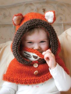 a little boy wearing a knitted hat and scarf with a fox design on it