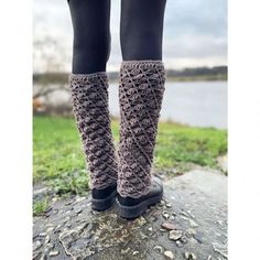 the legs of a woman in black boots and leg warmers standing on a rock