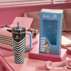 a pink desk with an old typewriter, coffee cup and book on it next to a blue box