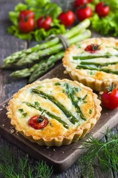 asparagus, tomato and cheese quiche on a cutting board with fresh herbs