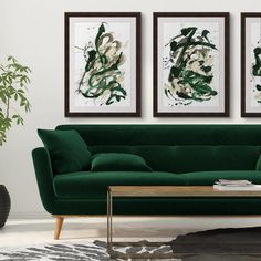 a living room with two green couches and paintings on the wall above them, along with a coffee table