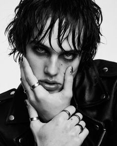 a man with black hair and piercings on his fingers is posing for a photo