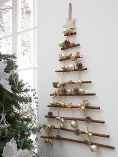 a christmas tree made out of wooden sticks and ornaments hanging on the wall next to a window