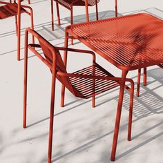 an orange table and some chairs on a white floor with shadows from the sun shining through them