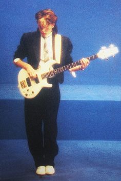 a man in a suit and tie holding a guitar