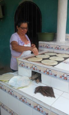 a woman making tortillas on top of a counter