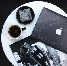 a white plate topped with an apple laptop next to a cup of coffee and photos