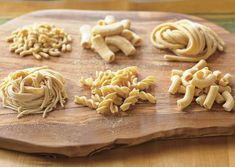 several types of pasta on a wooden cutting board