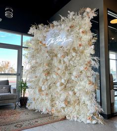 a large white christmas tree with flowers on it's side in an office lobby