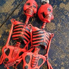 three red and black skeleton keychains on top of a wooden table with two keys in the shape of skulls