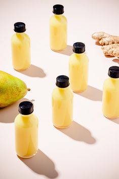 several bottles of liquid next to a pear and ginger